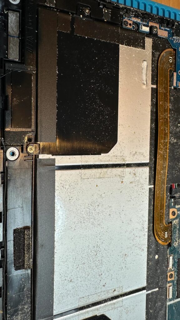 A imagem mostra a parte interna de um laptop sem marca, revelando acúmulo de poeira em vários componentes e conectores visíveis na placa-mãe.
