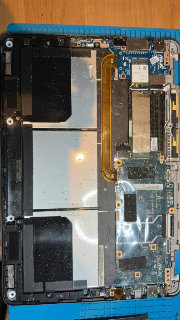 Os componentes internos de um laptop ASUS estão expostos, mostrando a placa-mãe, os conectores e os circuitos, com o logotipo da ASUS visível na placa de circuito.